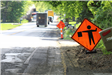 Flagger sign on Seymour Lake Rd. ahead of Preservation Overlay paving in Oxford Charter Township