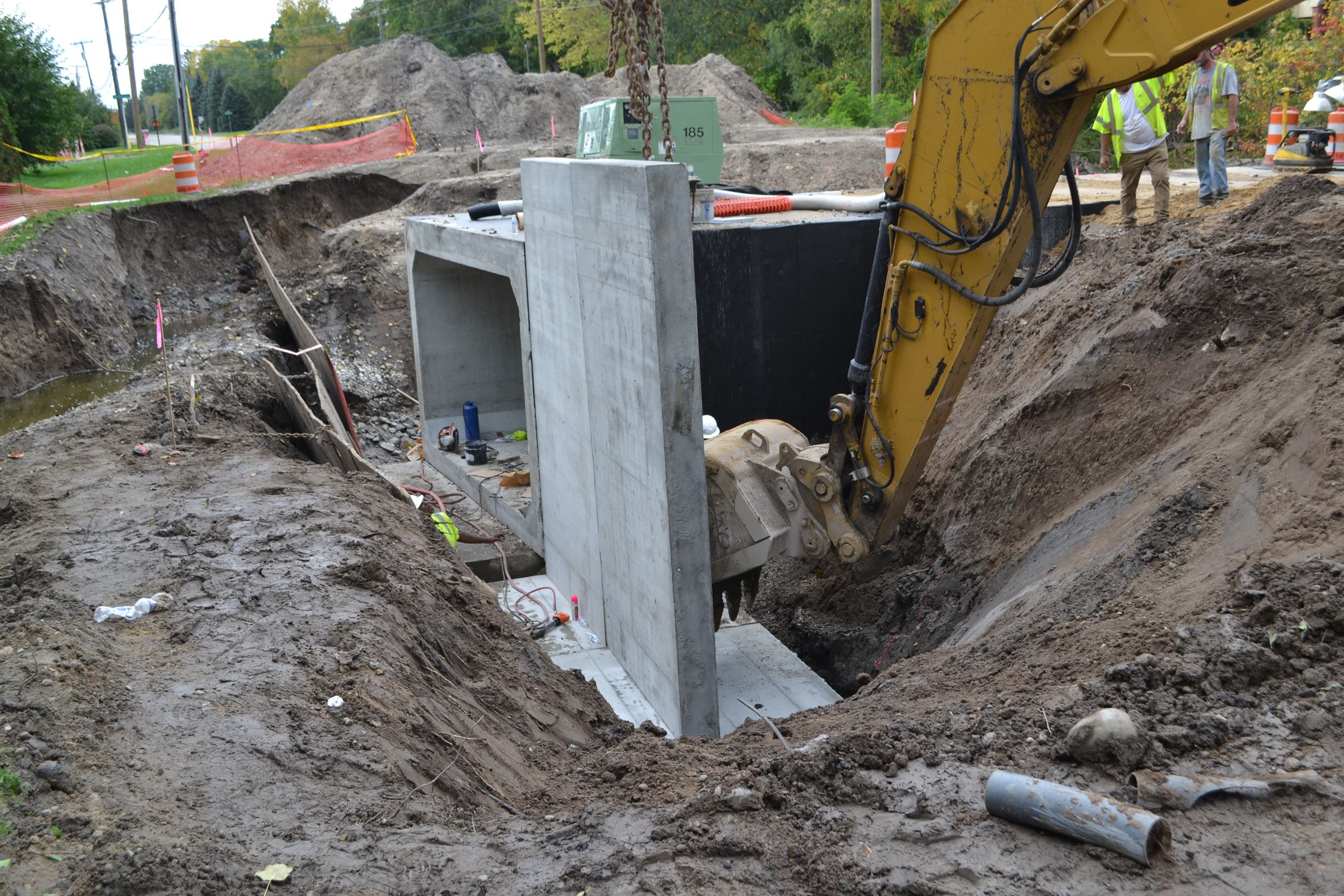 Excavator pushing wing wall to final position