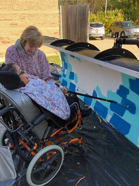Side View of a Student Using a Roller to Paint a Plow