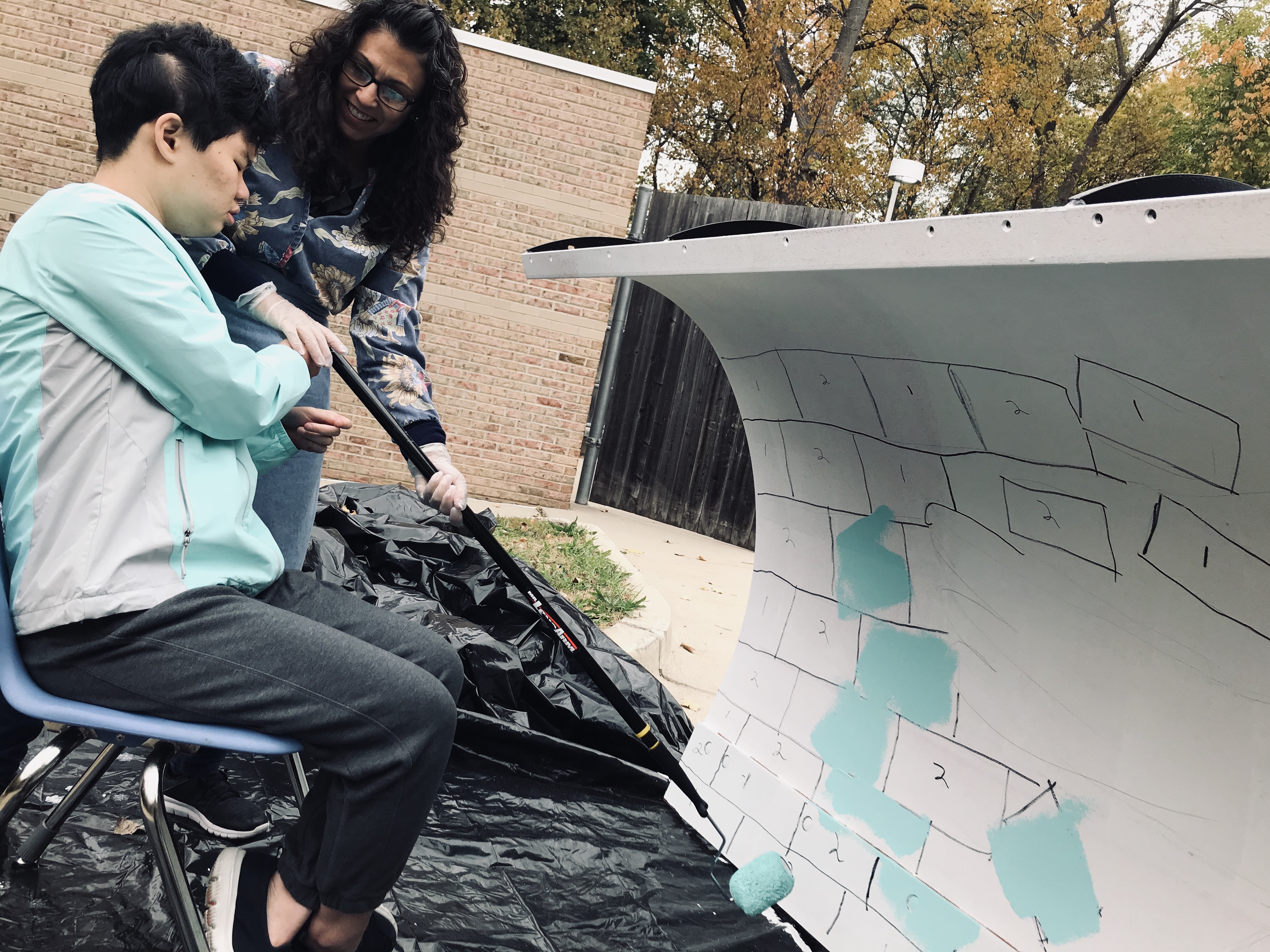 Student Using a Roller to Paint the Plow Template