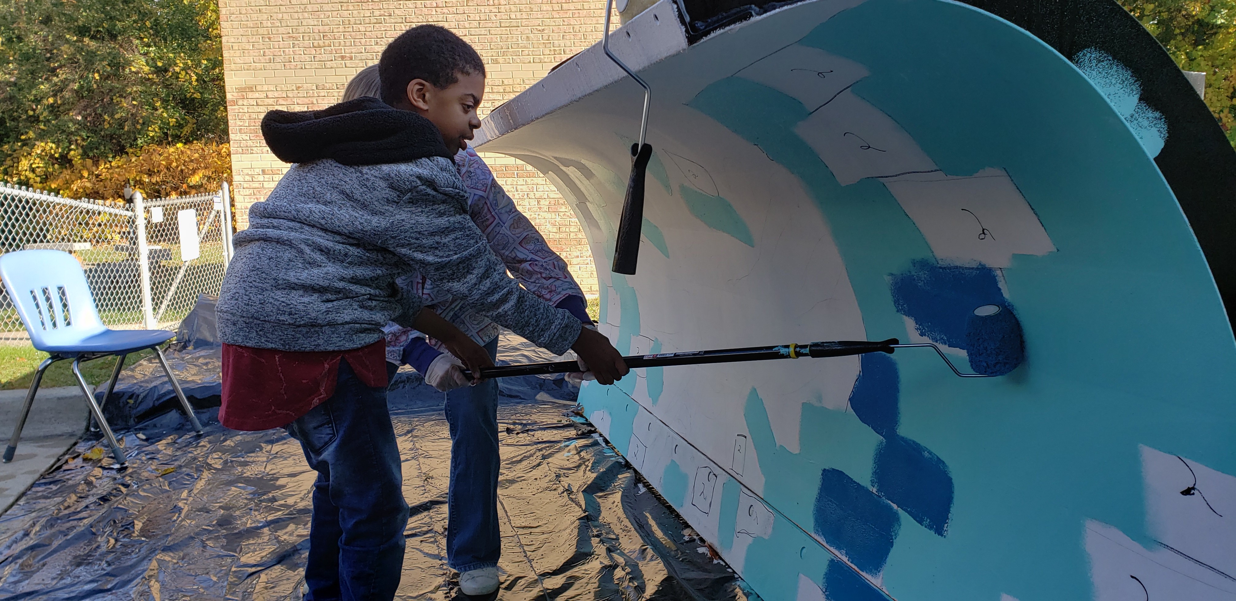 Student Painting the Plow with a Roller