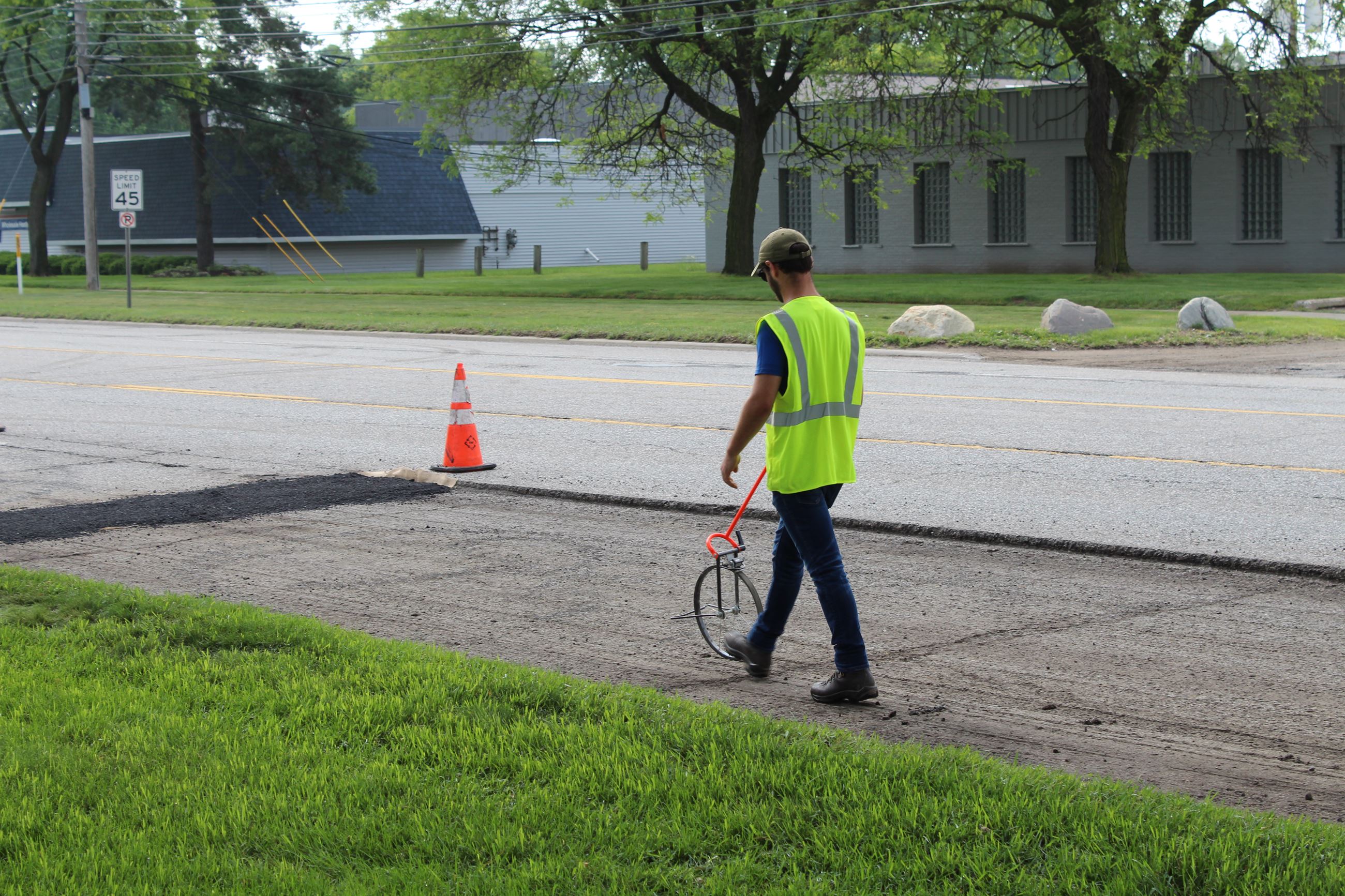 RCOC intern Jacob Barth measuring the length of an 8 Mile road spot resurfacing section
