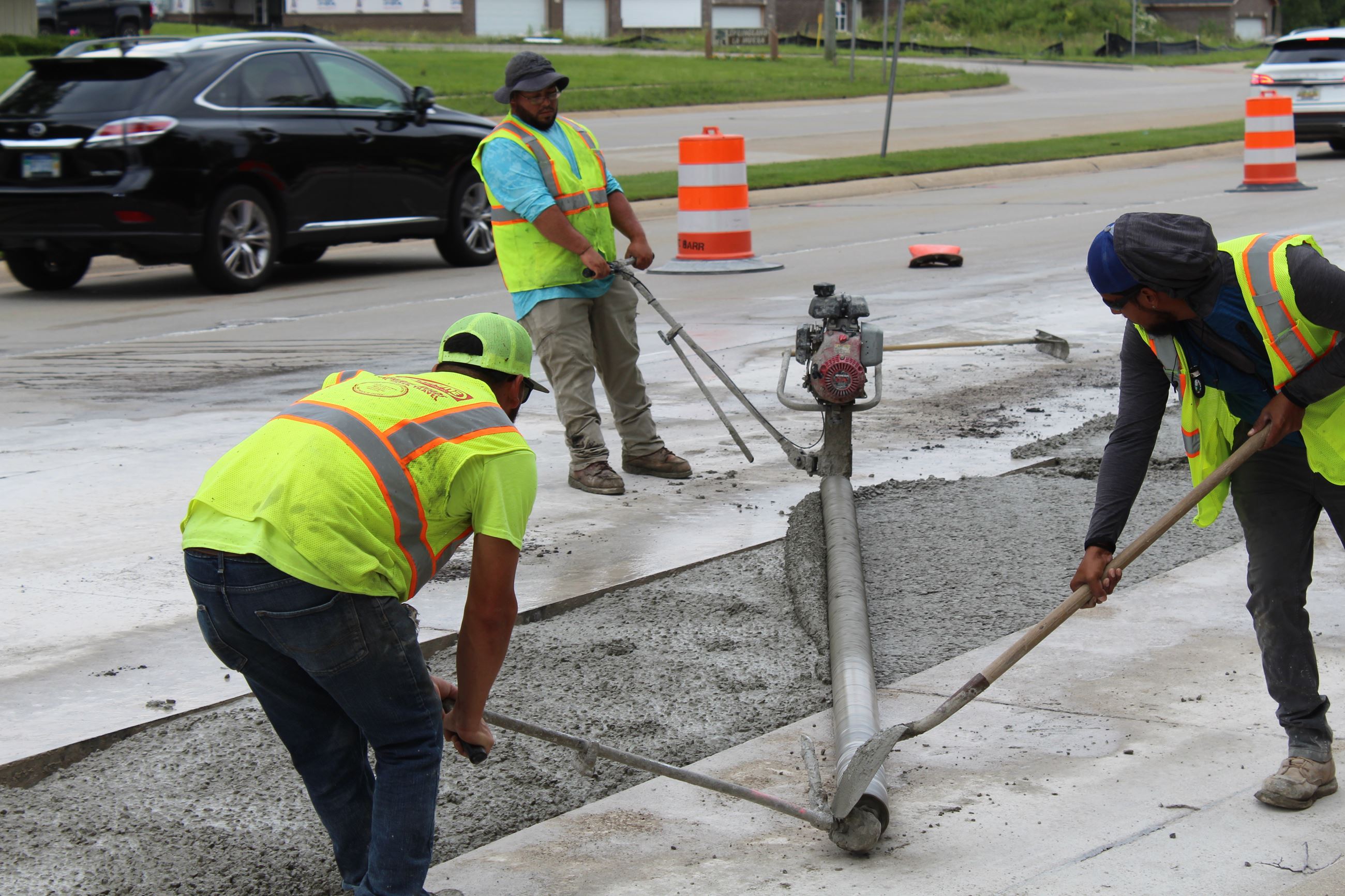Workers use vibration roller to compact concrete on Orchard Lake Rd