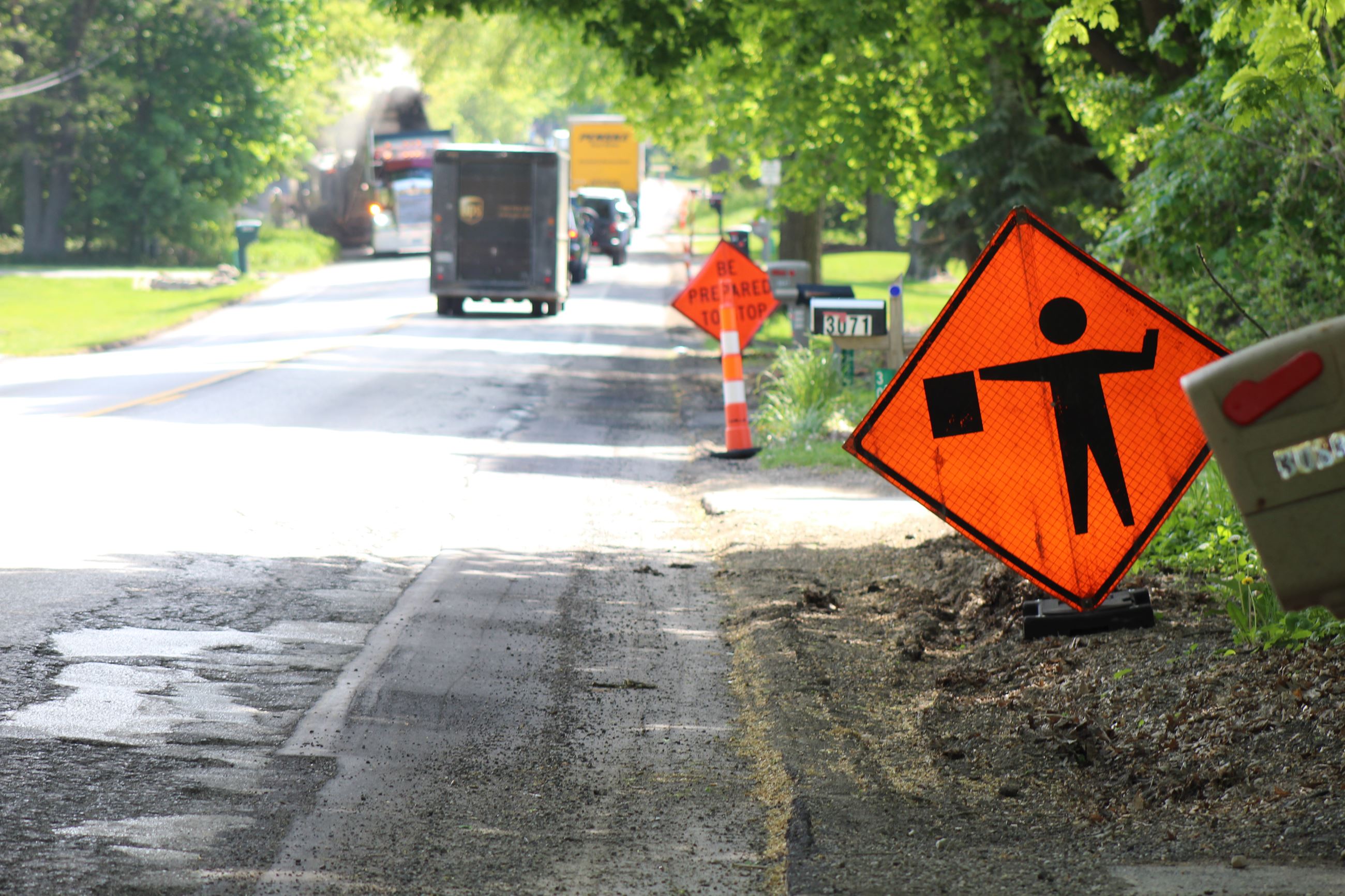 Flagger sign on Seymour Lake Rd. ahead of Preservation Overlay paving in Oxford Charter Township